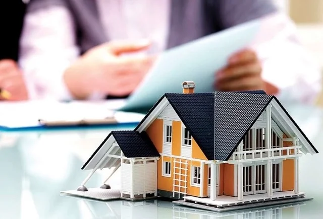 A person reviewing documents behind a model house.