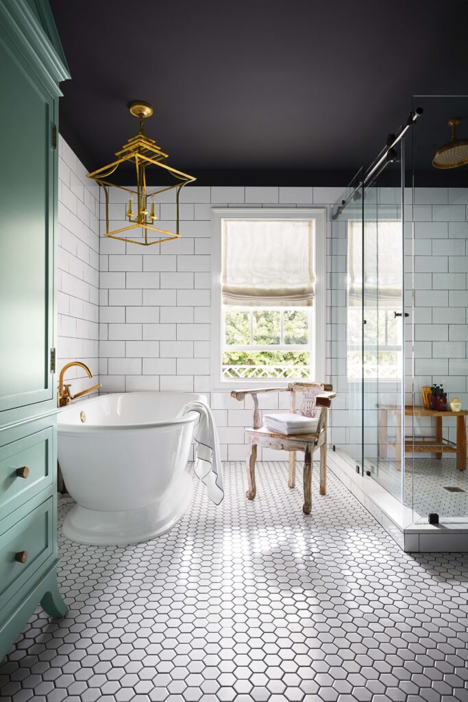 Bright bathroom with a freestanding tub, glass shower, and patterned floor tiles.