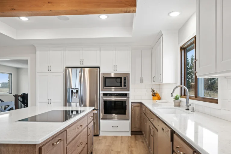 Modern kitchen with white cabinets and stainless steel appliances.